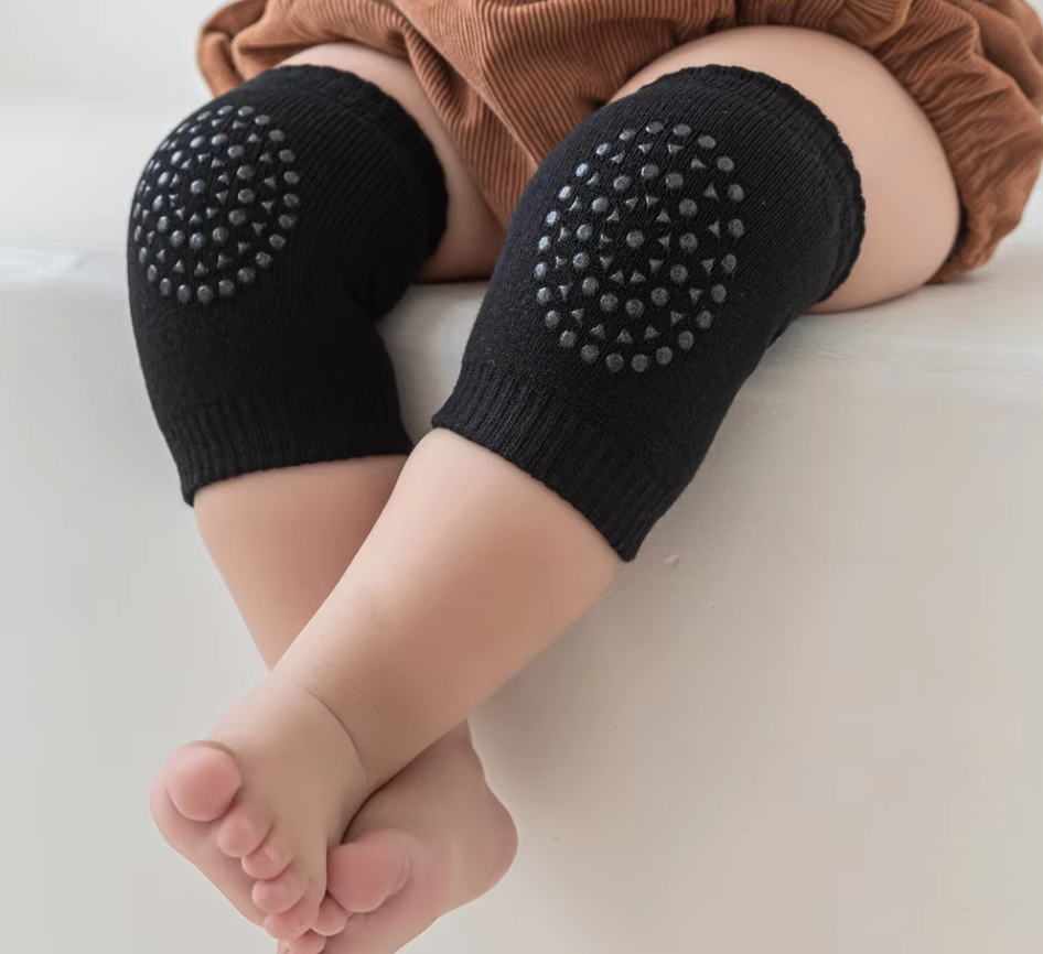Kids knee sleeve worn on both knees of a baby in a black color, highlighting textured grip pads during floor movement.